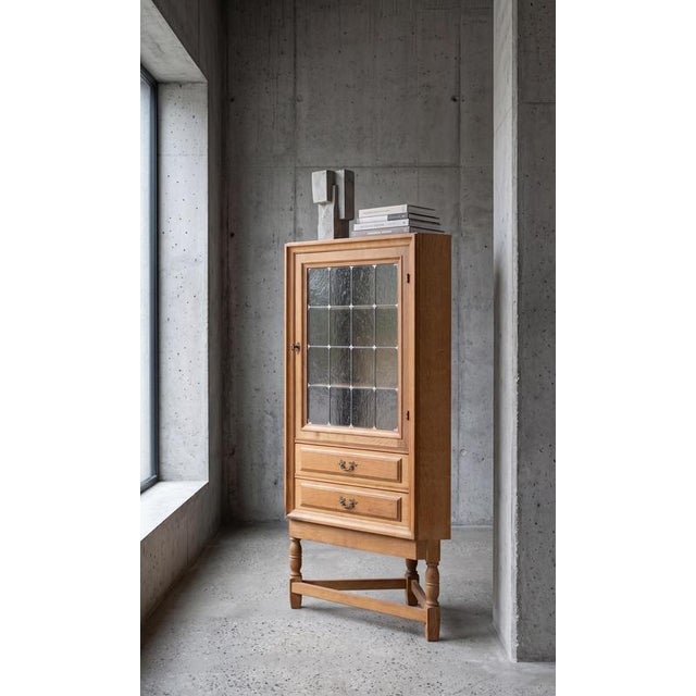 Oak corner cabinet attributed to Danish designer Henning Kjærnulf, crafted in Denmark during the 1960s. Designed in a...