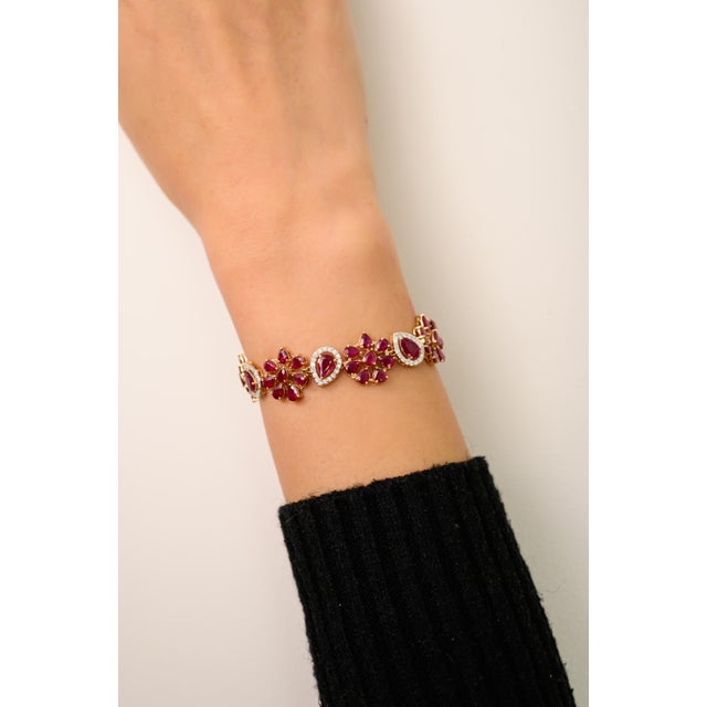 This floral bracelet features pear cut ruby totaling 12.37 carats, set in rich 14k yellow gold. Accented by round...