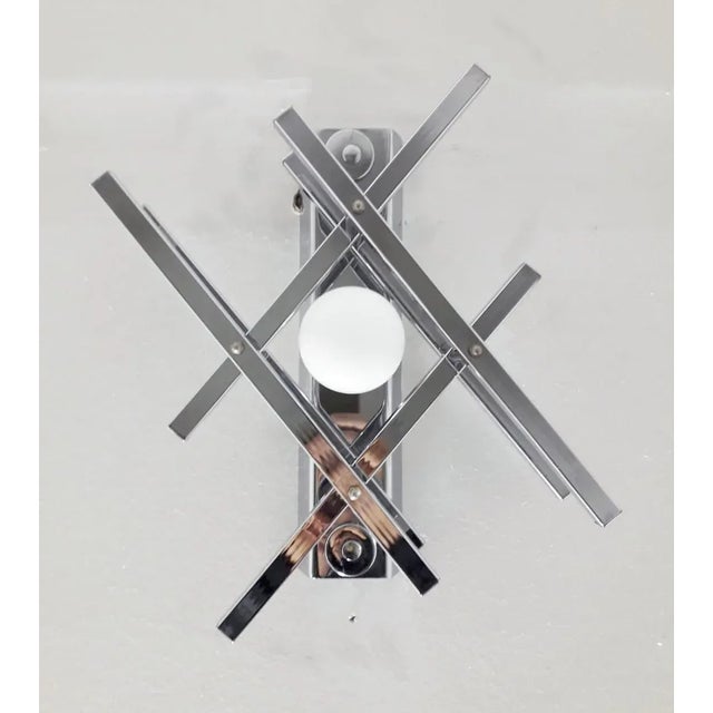 Excellent vintage condition midcentury Italian wall lights formed with geometric chrome arms that enclose a single light...