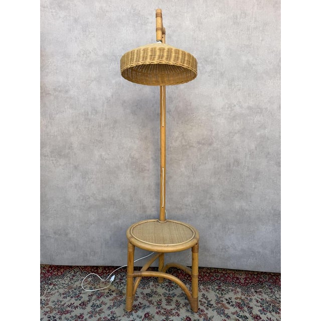 Rattan floor lamp with integrated side table, in the style of Tito Agnoli, 1960s. Bamboo and rattan floor lamp with a...