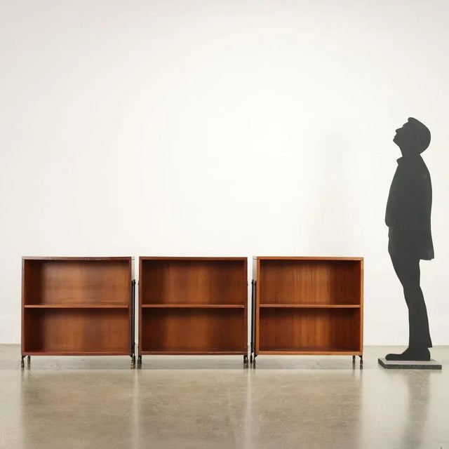 Group of 3 open units, teak veneered wood, top covered in laminate, enamelled metal legs with adjustable brass feet. This...