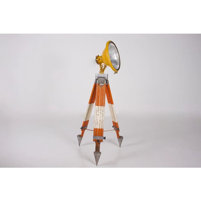 Construction site headlight with fresnel holophane lens mounted on an adjustable theodolite tripod, a leather strap holds...