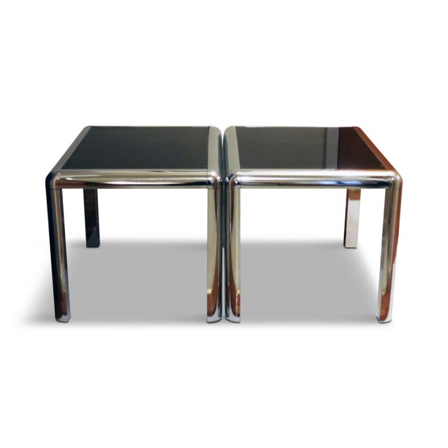 A captivating pair of 1970s chrome and glass side tables in the style of Milo Baughman and John Mascheroni. Showcasing the...
