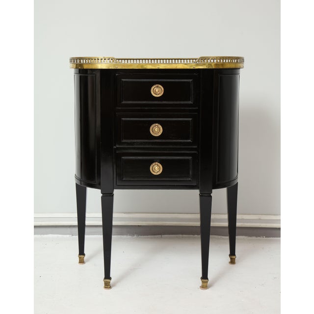 Pair of ebonized French marble-top petite commodes with brass gallery and pull-out drawers.