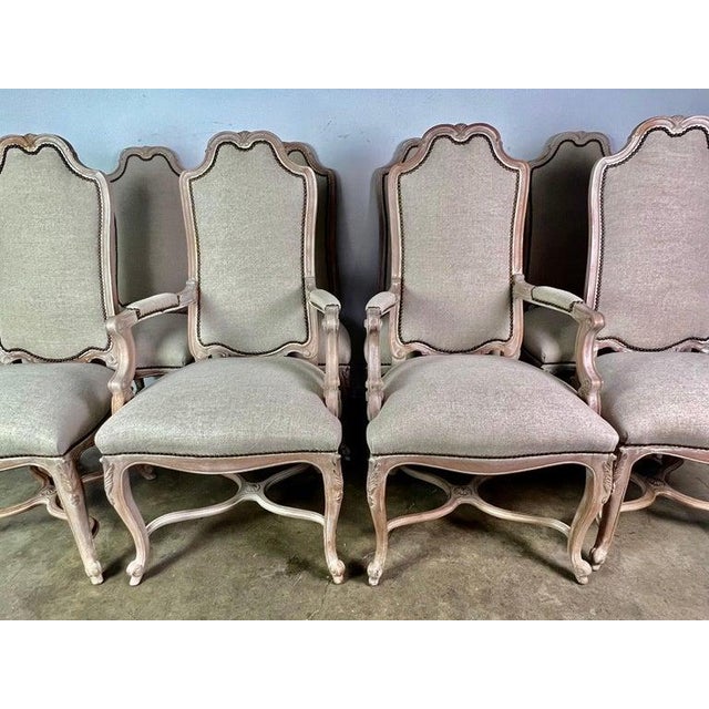 Set of (8) French Louis XV style dining chairs in a bleached walnut wood. The chairs are newly upholstered in a washed...