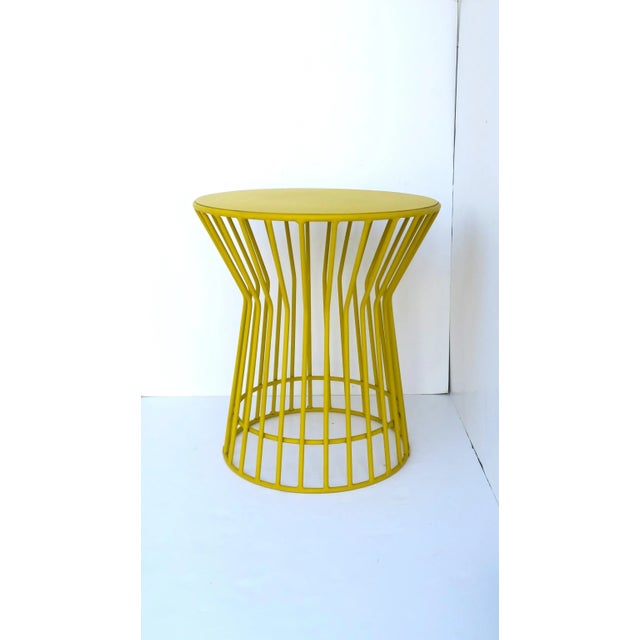 A round yellow powder-coated metal end or side table with hourglass design, in the Midcentury Modern or Postmodern design...