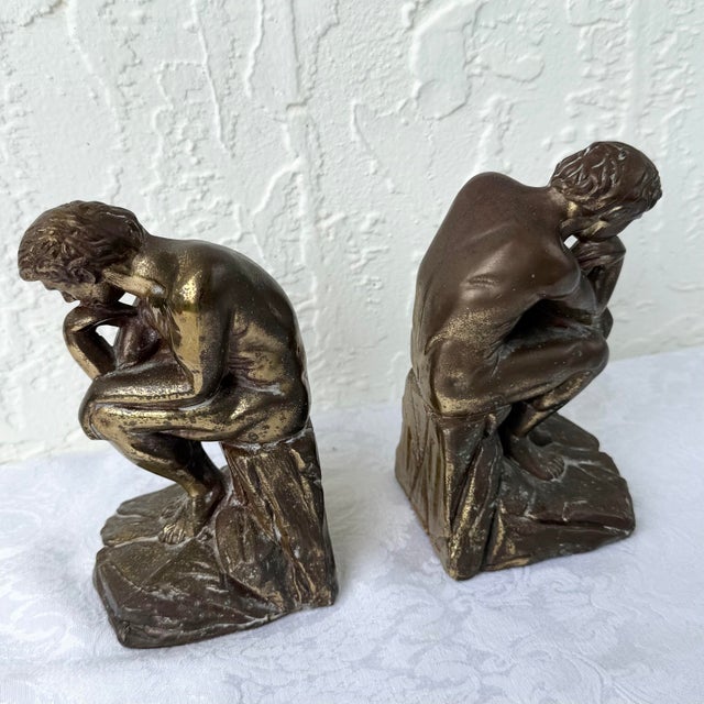 A striking pair of vintage brass bookends inspired by Auguste Rodin’s iconic The Thinker, featuring sculptural nude...