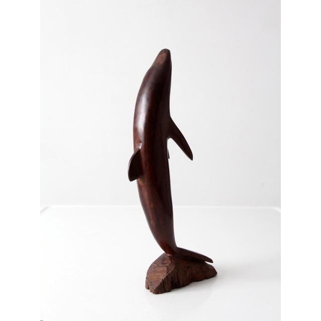 This mid century ironwood dolphin sculpture features a streamlined carved form rising from a natural wood base with rich...