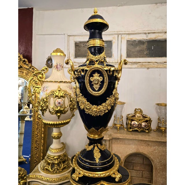 This grand Sevres-style porcelain vase is an elegant statement piece finished in rich midnight blue tones that become even...