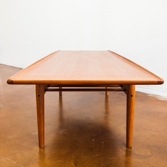 Refinished surfboard coffee table with slatted magazine shelf by Grete Jalk c. 1960s. At 63 inches in length, it has the...