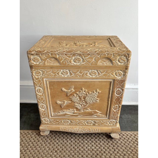 Carved wooden storage chest in a neutral blonde hue. Ornately sculpted with reliefs depicting Asian themed birds and...