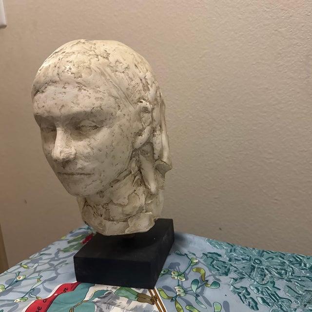 An expressive, hand-modeled plaster bust depicting a woman with a serene, introspective expression. This figurative work...