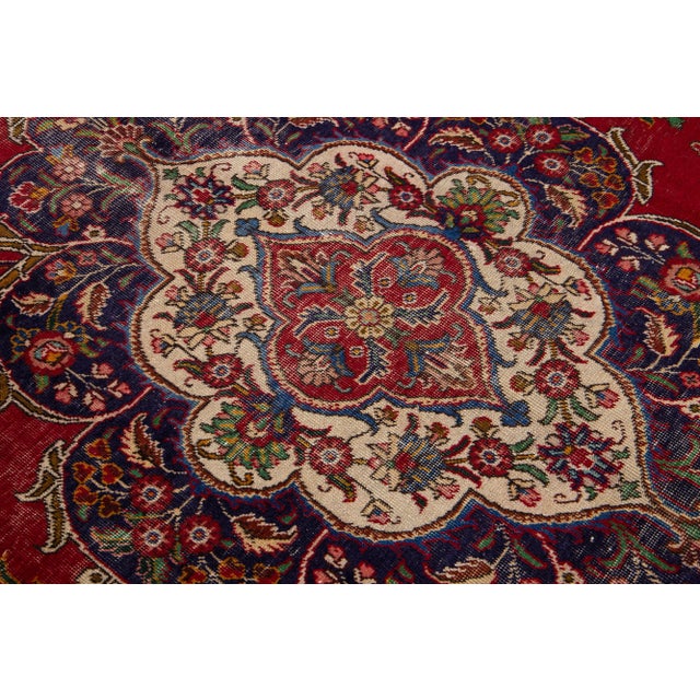Beautiful vintage Persian Tabriz hand-knotted wool rug with a red color field. This piece has a navy blue frame and...