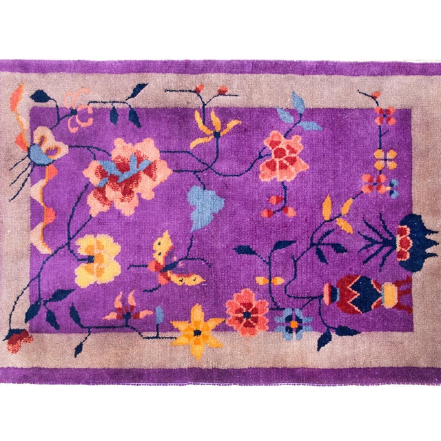 An early 20th century Chinese Art Deco rug with a violet field surrounded by a wide gray border, and overlaid with a...