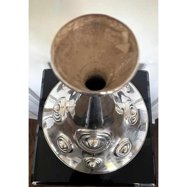 A large sterling silver vessel in an asymmetrical hour-glass vase form with a larger upper conical body balanced on a much...