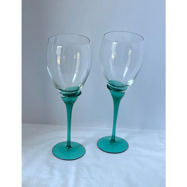 A striking pair of Italian Murano-style art glass wine goblets featuring clear rounded bowls over elongated teal green...