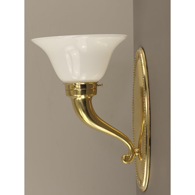 Massive brass wall lamp with opal glass shade. Polished surface. The light provides a pleasant, glare-free light. European...