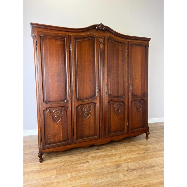 An elegant Vintage French Louis wardrobe with a substantial four-door design, decorative carved detailing, shaped upper...