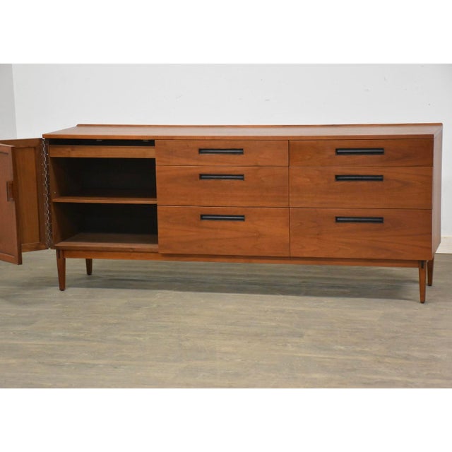 A mid century modern walnut sideboard credenza or dresser with a bifold door designed by Kipp Stewart for Directional by...
