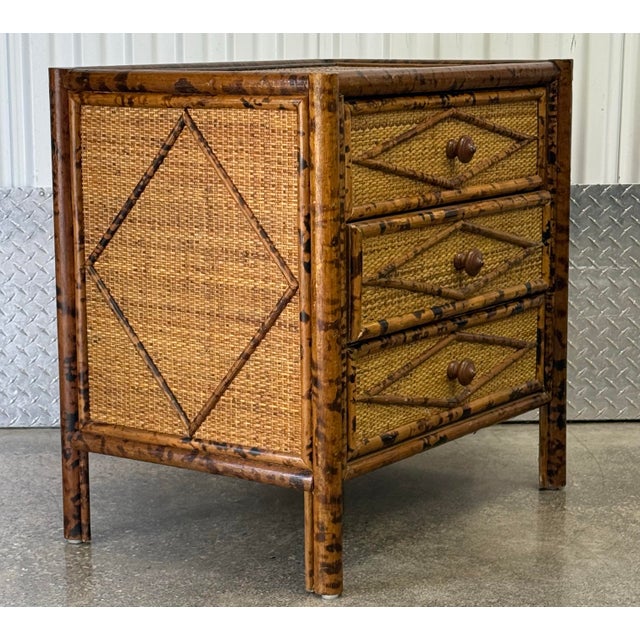 Stylish three drawer night stand crafted in wood with a faux bamboo frame having a faux tortoise finish and grasscloth...