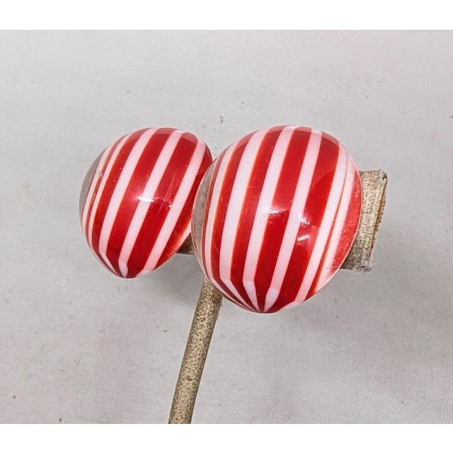 1970s gold-tone round domed clear resin clip earrings with red and white stripes. Marked crown "TRIFARI©" on the clips....