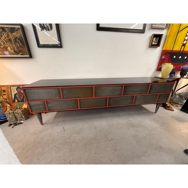 A stunning statement piece, this credenza has a one piece black smoked glass top with 11 brushed steel front push open...