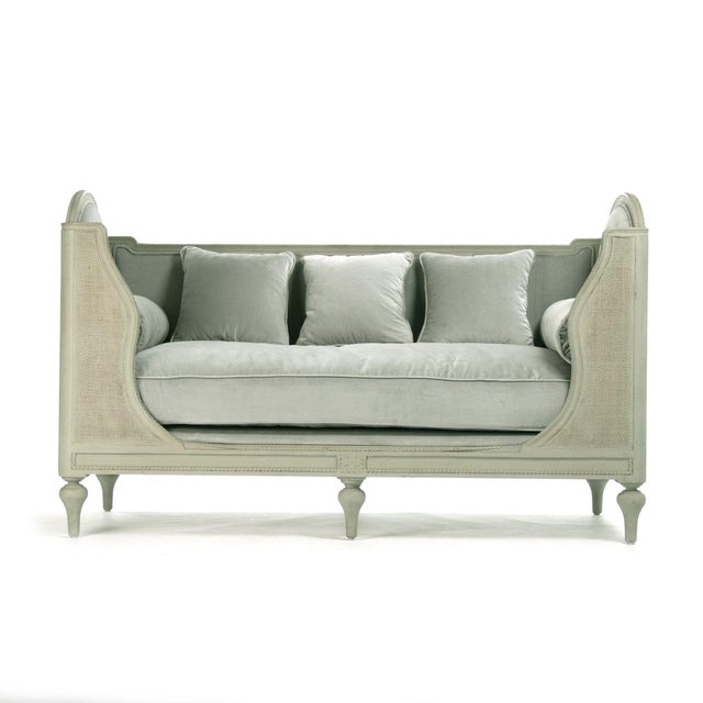 The Winni Daybed from Zentique is a French country daybed with light grey-green velvet upholstery on a distressed grey-...