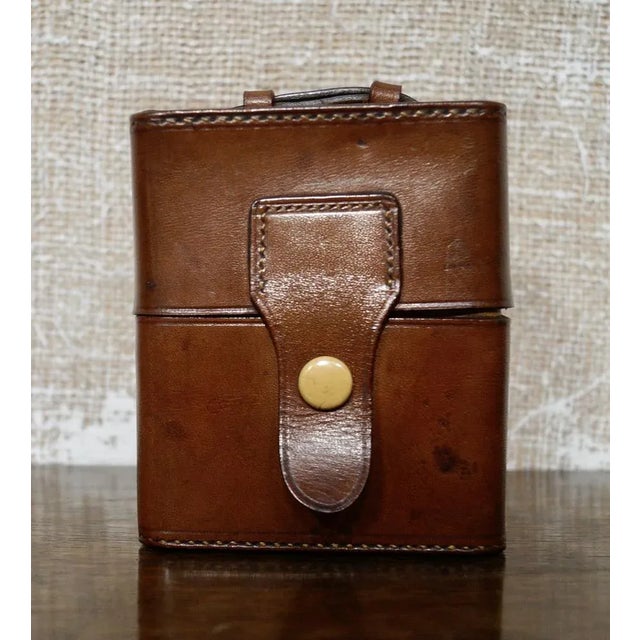 A pair of travel glass cologne bottles in a leather case. Each bottle has a silver plated screw on cap and a small glass...