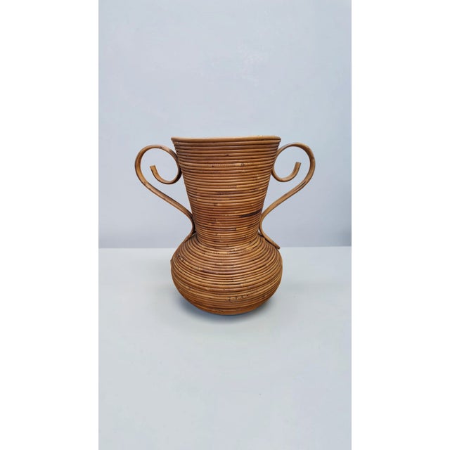 Large amphora vase made of curved wicker, produced by Vivai del Sud. The honey color, typical of the material and finish,...