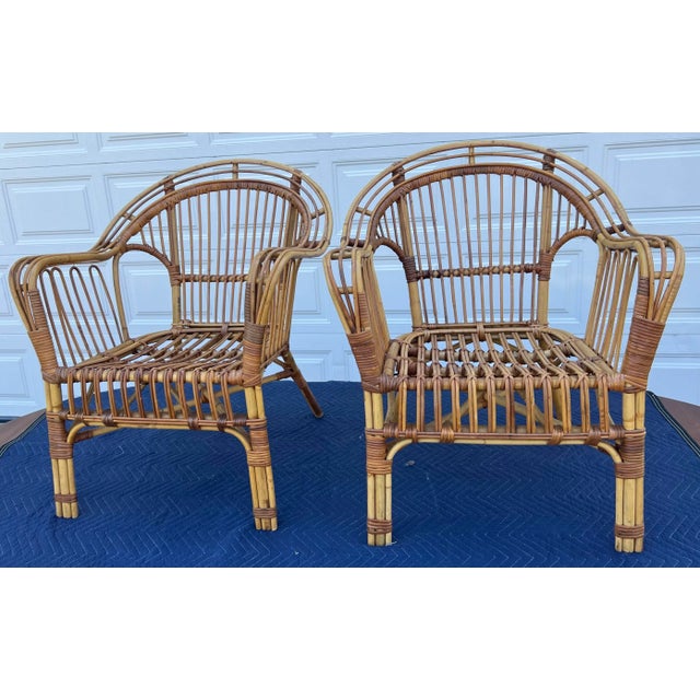 A stylish and inviting pair of vintage rattan barrel lounge chairs, showcasing a classic coastal silhouette with warm...