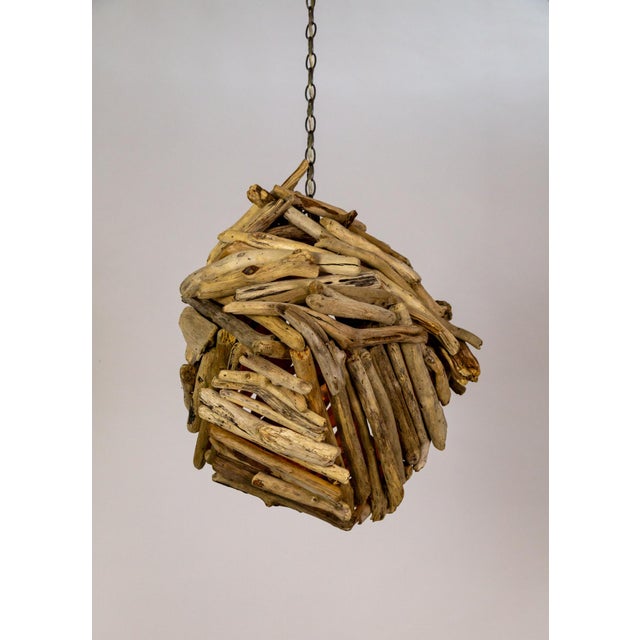A large, one-of-a-kind pendant light comprised of pieces of driftwood meticulously placed into a bundle. It has two medium...
