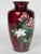 A striking red Japanese ground vase made of enamel. The front of the vase features vibrant flowers in soft gradients of...