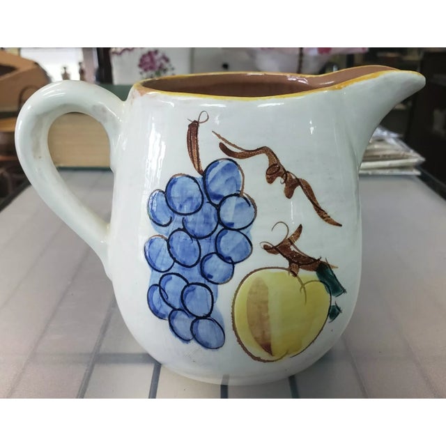 This is a Vintage Stangl Pottery Ceramic Fruit Motif Pitcher. It measures 4 15/16" tall, 6 3/4" wide and 4 1/2" deep. The...