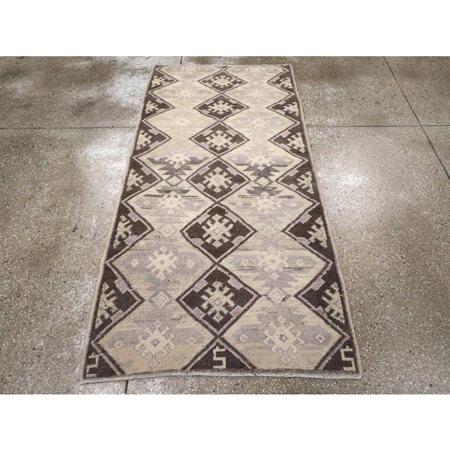 This mid-20th century Turkish Anatolian rug, measuring 3' 2" x 6' 7", presents a striking tribal aesthetic defined by its...