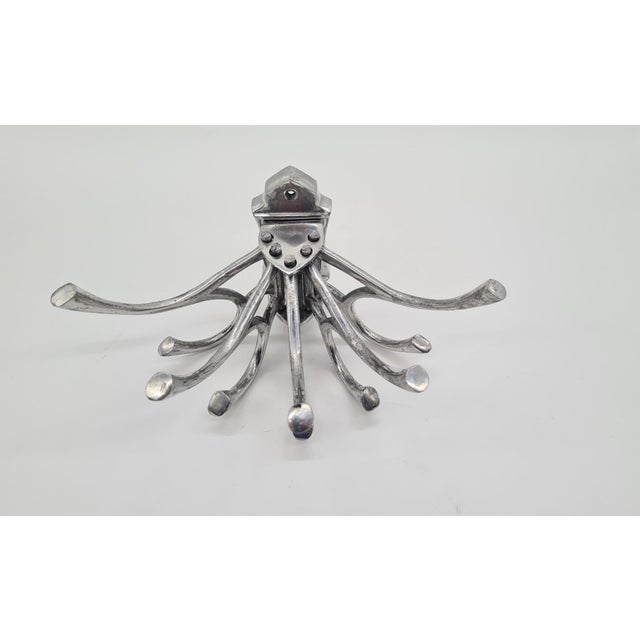 A wall hanger made of aluminum, with a very distinctive, sculptural form. The hanger has many contoured arms/hooks, which...