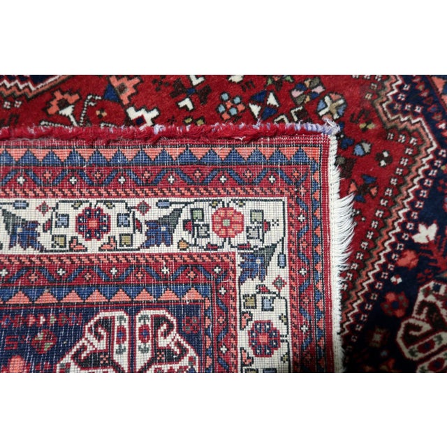 A handmade antique Persian Qashqai rug from the 1920s, woven in wool and showcasing the bold tribal artistry of the...