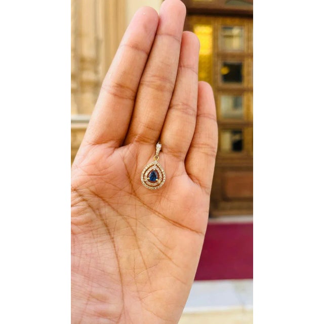 Diamond Blue Sapphire Pendant in 18K Gold studded with pear cut sapphire and round cut diamonds. This stunning piece of...