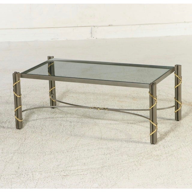 Modernist design constructed with mixed metal finishes and glass. The table is anchored by an inset glass top set within a...