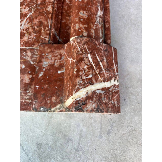 Red campan marble fireplace in the louis xiv style, late 19th century. The mantel features a table at each end. The mantel...