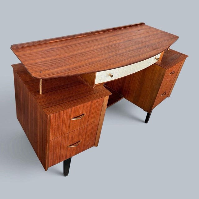 a lebus dressing table or desk with a floating top supported on brass-coloured fittings. Details circa 1950s–60s; teak-...
