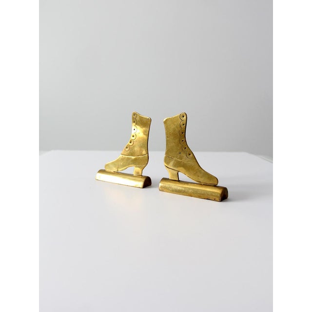 A pair of antique brass mantel ornaments shaped as Victorian ladies’ boots. Each features delicate scalloped detailing...