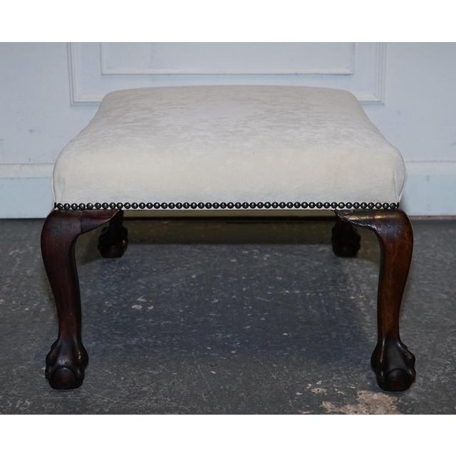 A charming early Victorian footstool featuring classic carved claw-and-ball feet and a beautifully upholstered white suede...