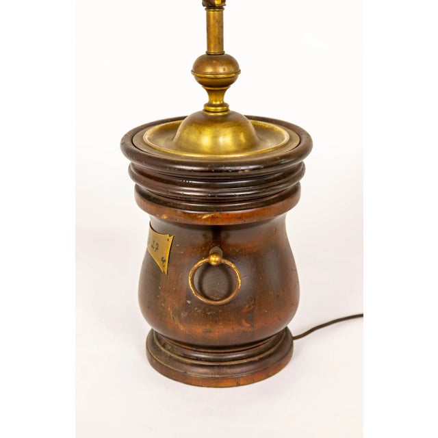 An American Colonial-style turned wood basin lamp with a prominent brass metal plate marked with "1827", a clover, and a...