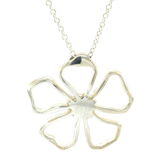 A distinctive Tiffany & Co. daisy flower pendant necklace crafted in sterling silver, featuring a bold floral motif with a...