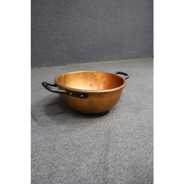 Antique solid copper mixing bowl featuring a rounded form with hand-forged iron side handles secured by copper rivets. The...