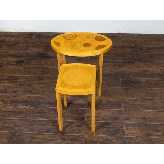 A pair of Baker Furniture Company Art Deco style wooden nesting tables from the 20th century made of an oval table and a...