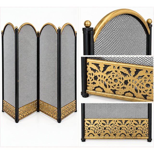 A vintage four-panel folding fireplace screen featuring black metal mesh with warm brass accents. Each panel has a...