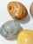 Set of five solid stone decorative eggs with polished surfaces and varied natural veining and banding. Colors range from...