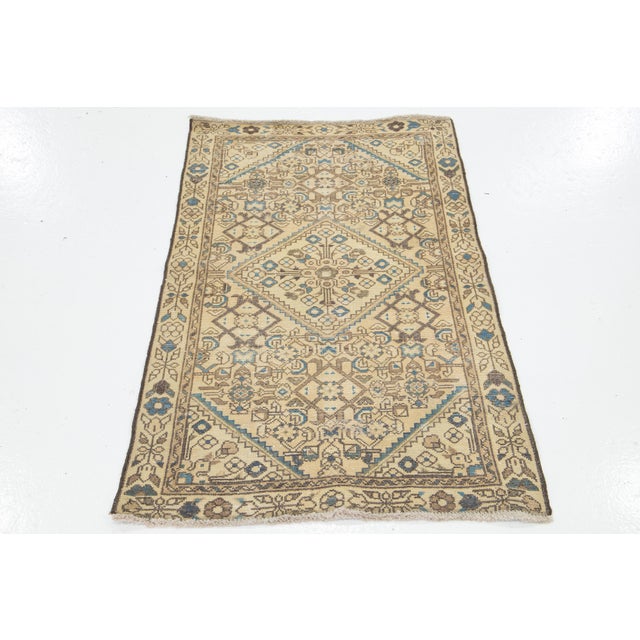 This vintage hand-knotted Persian rug has a beige field with accents in blue and brown throughout the design. This rug...