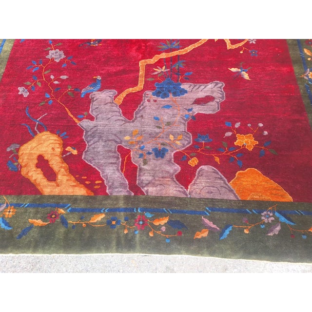 Vintage Chinese Art Deco rug featuring a richly saturated crimson field framed by an olive green border adorned with...